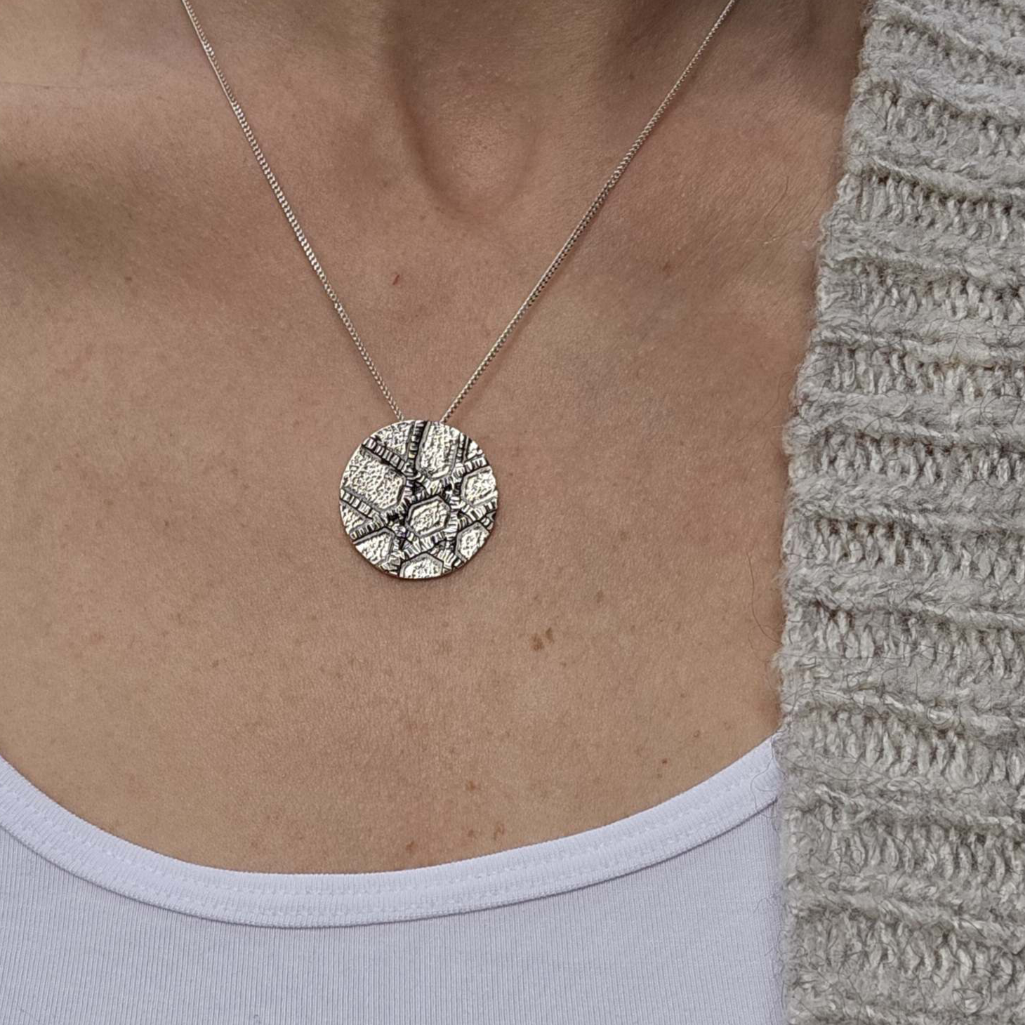 Silver Jewish Star Necklace worn around woman's neck with white shirt and grey sweater