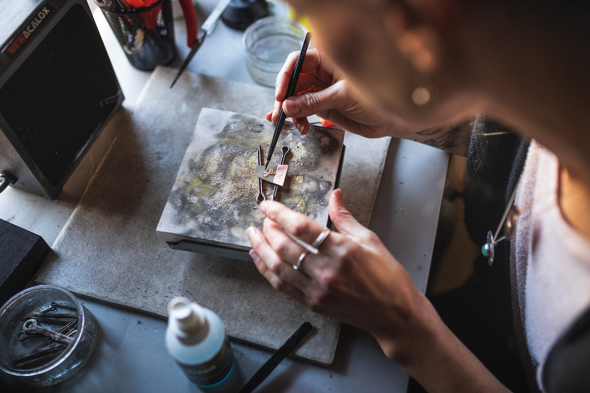 a woman using tools to make jewelry.