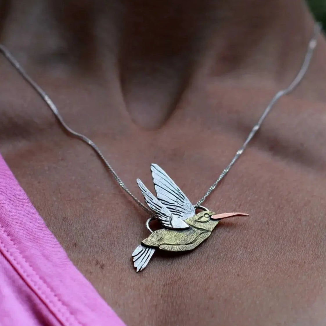 Woman in pink shirt wearing a custom designed handmade hummingbird necklace around her neck.