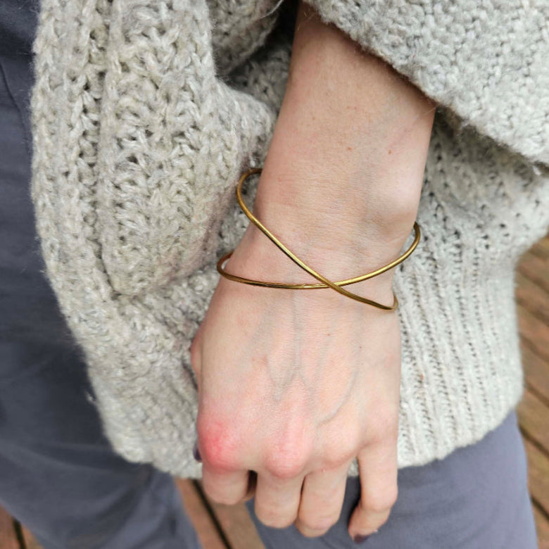 Woman in sweater and grey pants wearing Gold Infinity Bracelet