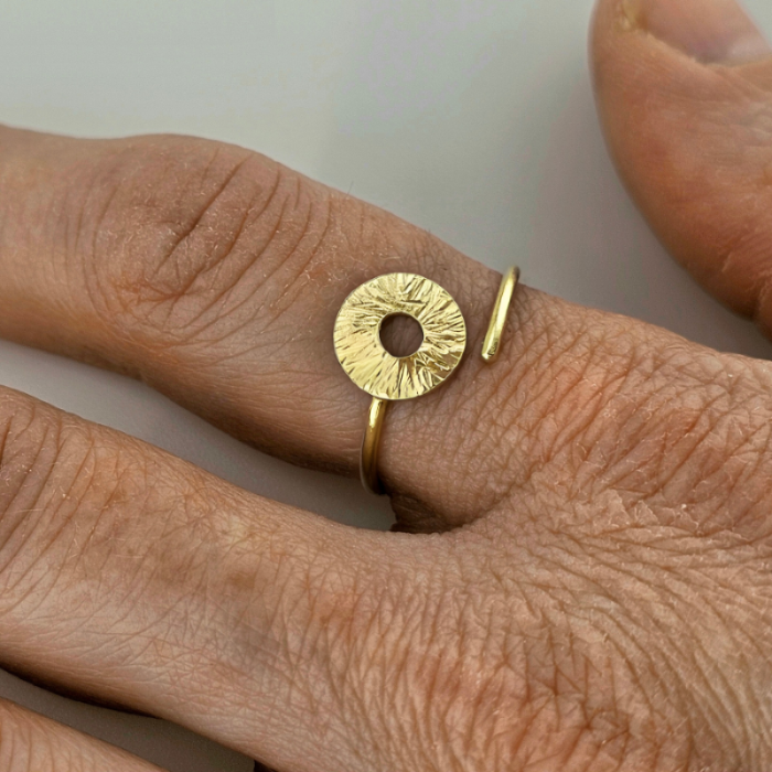 Gold manifestation ring on woman's pointer finger.