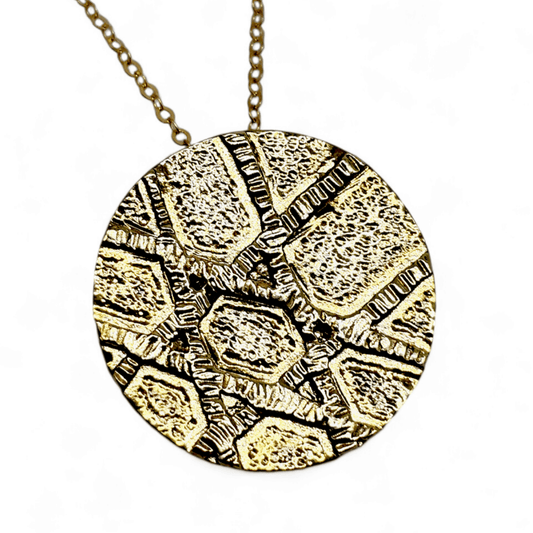 Gold circle pendant on a gold chain that has intersecting lines that form a Jewish Star on the bottom left.