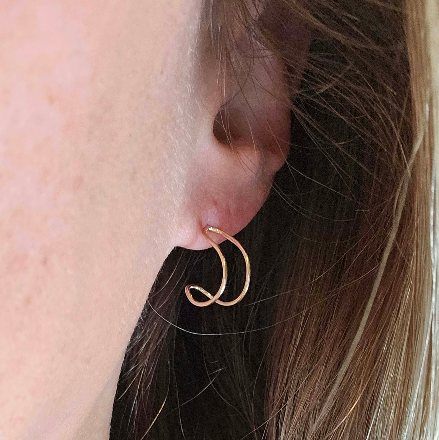 Woman's ear with half hoop shaped gold earring.