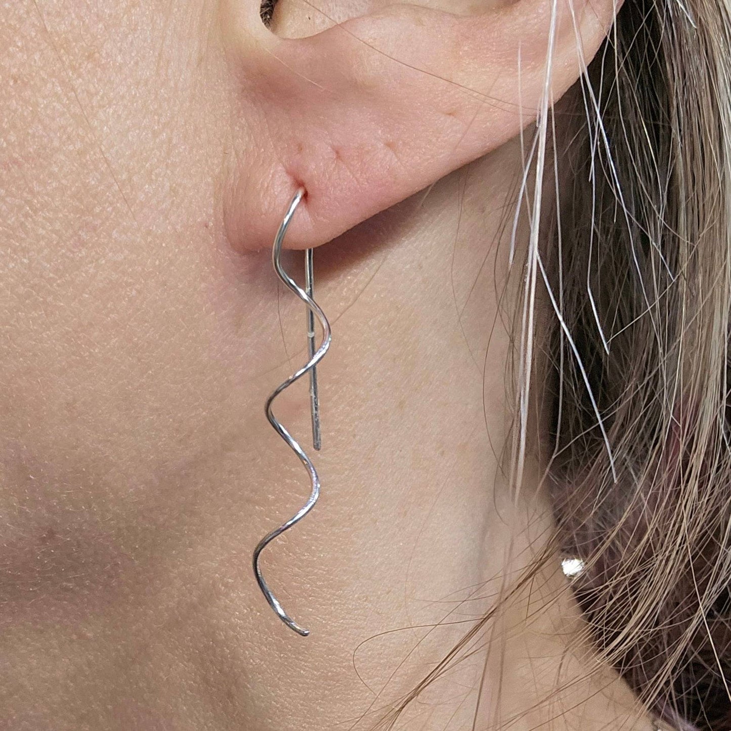 Close up of Woman's ear wearing silver spiral earrings by Jaclyn Nicole