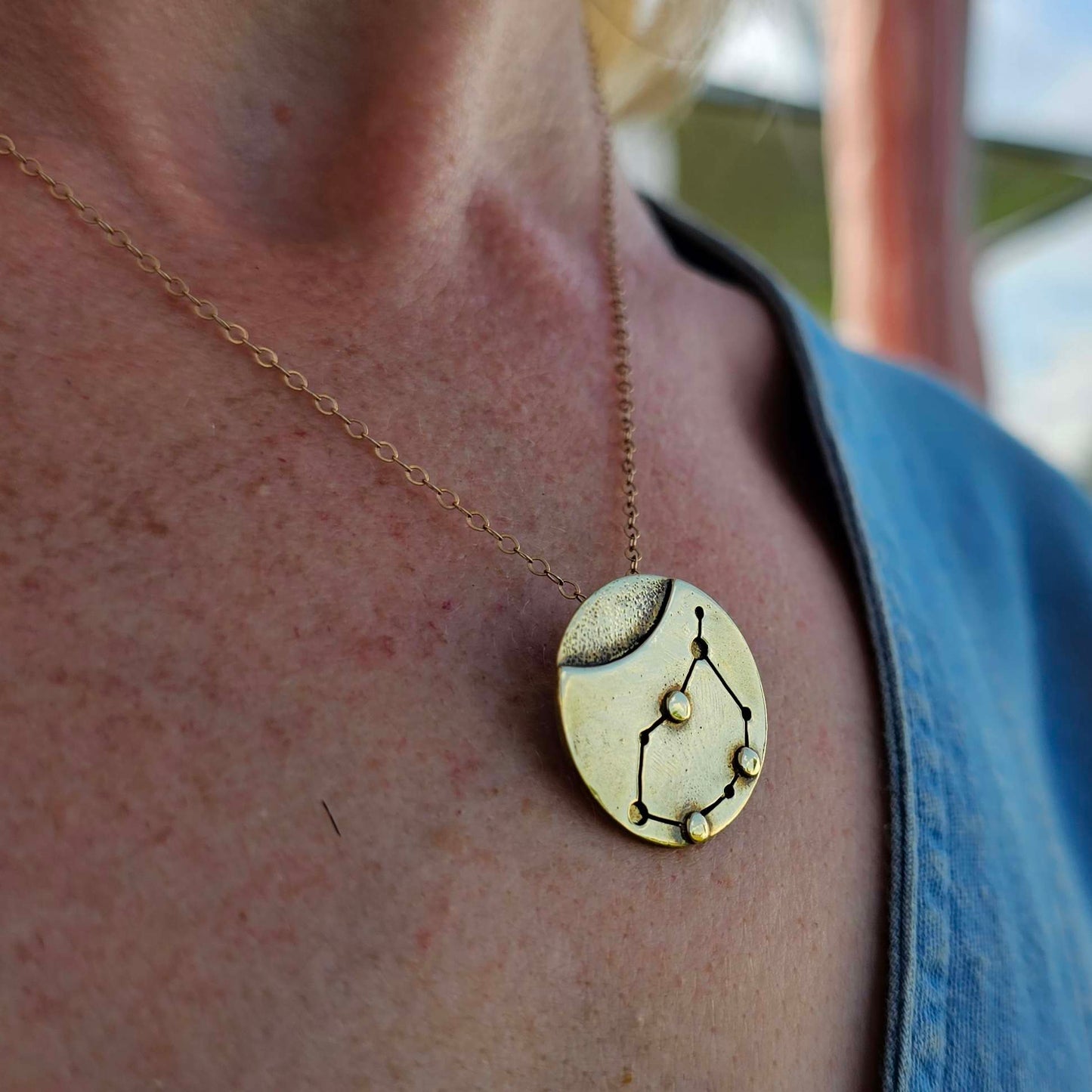 Close up of Gold Capricorn necklace on woman's neck