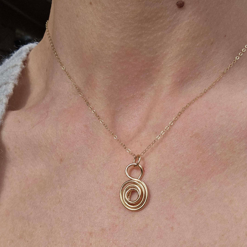 14K Gold g Gratitude Symbol Necklace worn on a woman's neck.