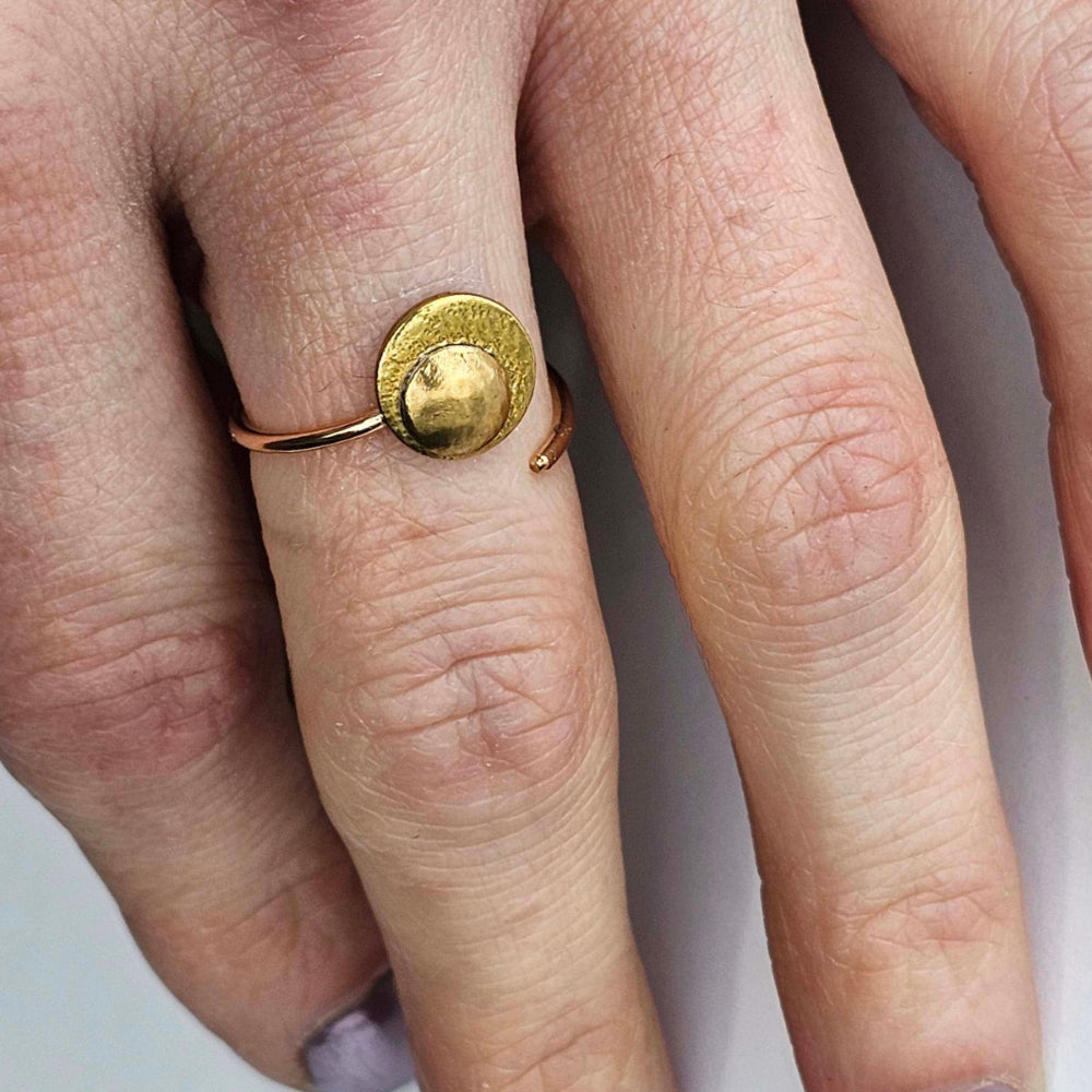 Woman's hand wearing a gold adjustable moon and stars ring on her index finger.