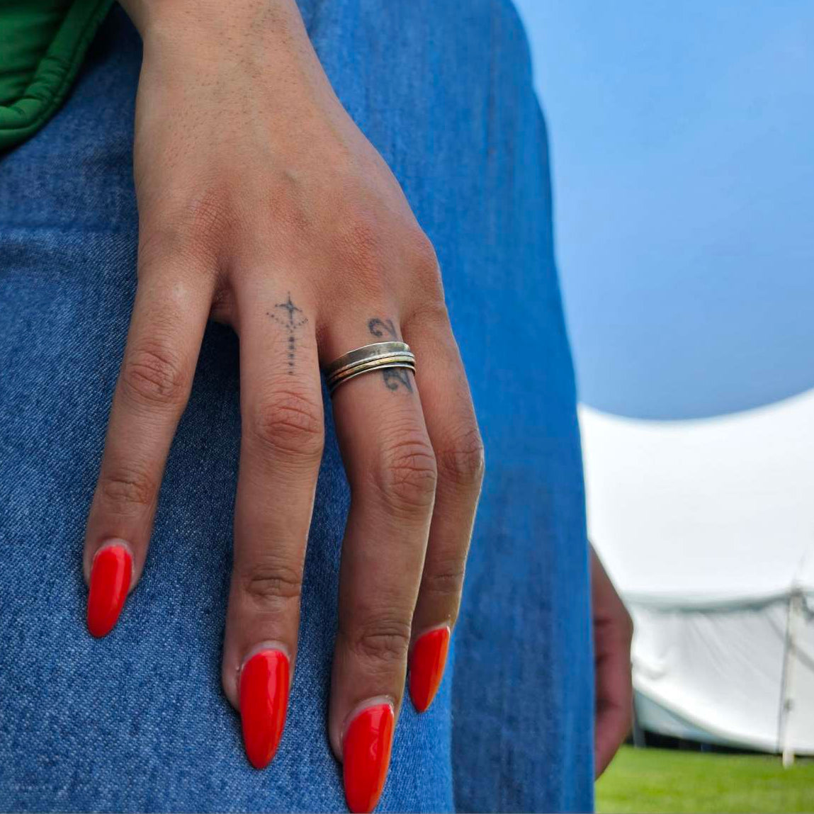 Woman's hand with tattoos wearing silver anxiety ring fidget.