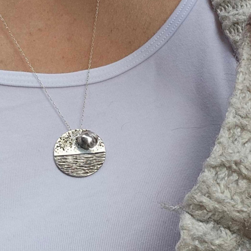 Woman wearing a Reflections domed moon necklace seascape in sterling silver 