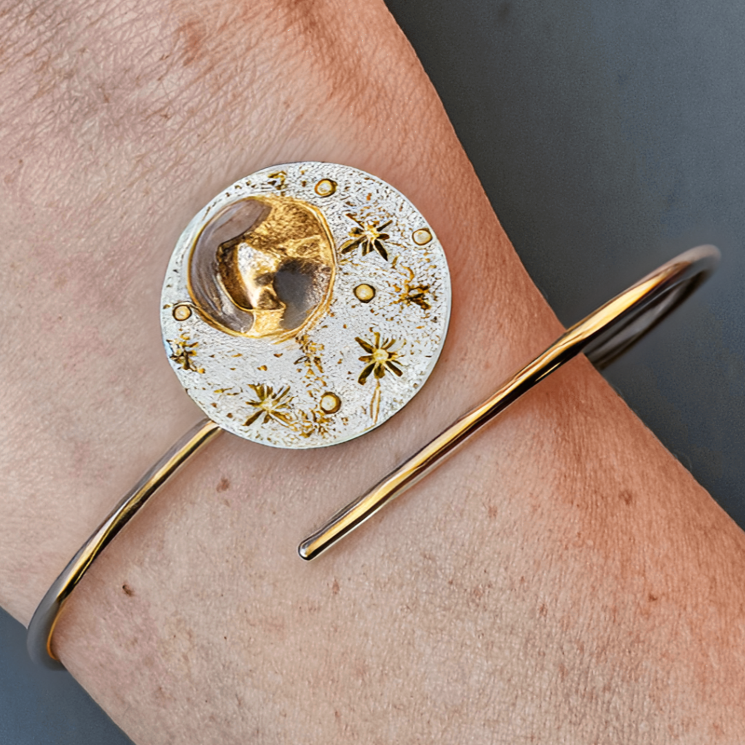 Reflections Moon bracelet in gold displayed on woman's wrist on grey background