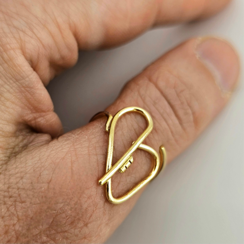 Woman's hand wearing a gold heart ring for self love on her thumb.