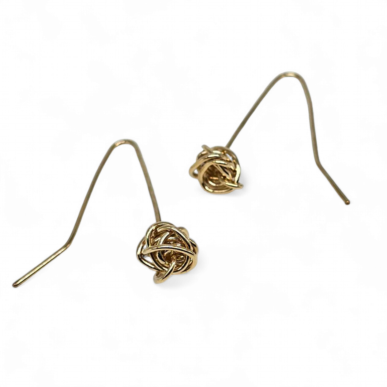 Close up of a pair of Drop Gold Handmade knot earrings on a white background.