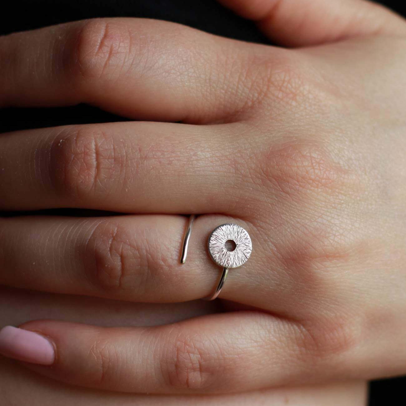 Woman's hand wearing a silver adjustable manifestation ring.