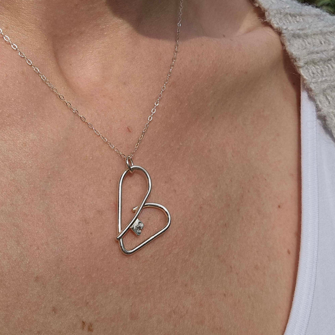 Woman wearing a silver heart key necklace/