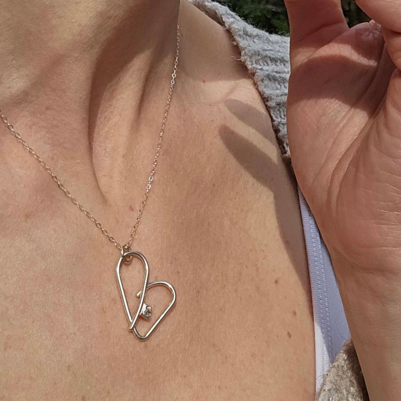 Woman wearing silver self-love key heart necklace.