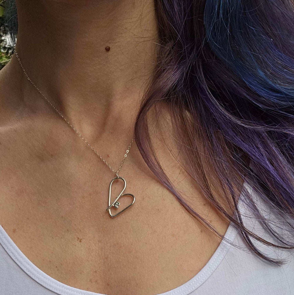 Silver self love key necklace worn on a woman's neck