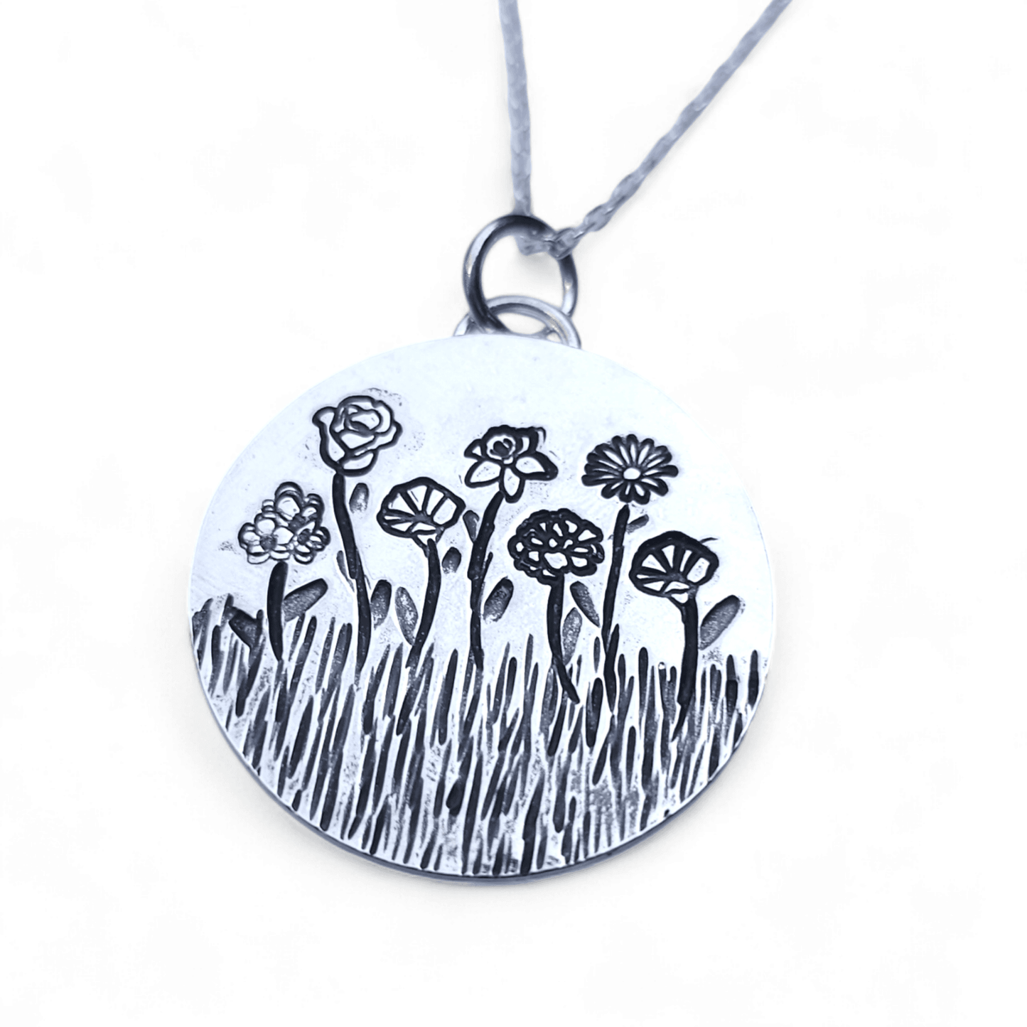 Silver necklace with birth month flowers of the wearers loved ones on a white background.