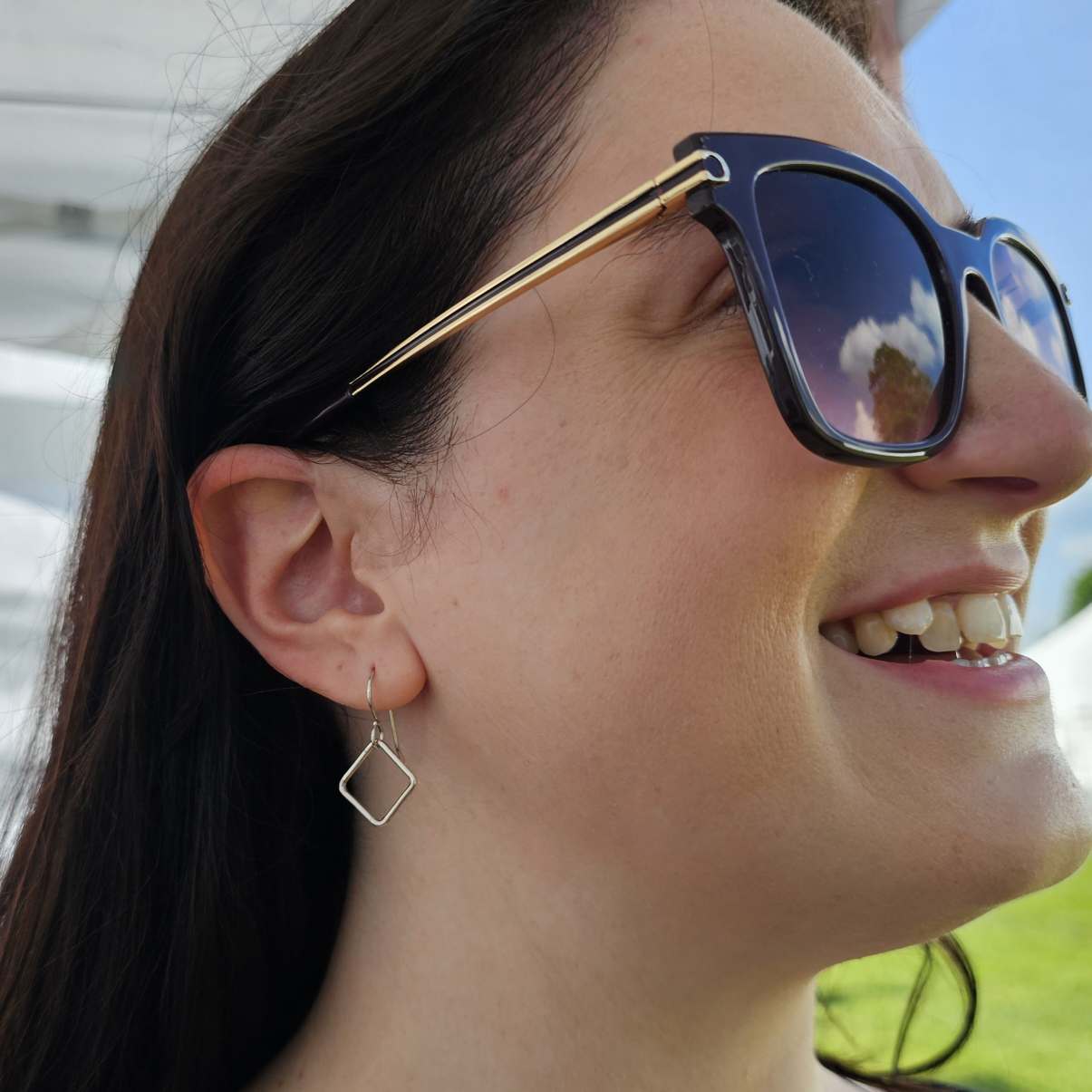 Smiling woman with sunglasses wearing dangle Silver Box Breathing Earrings