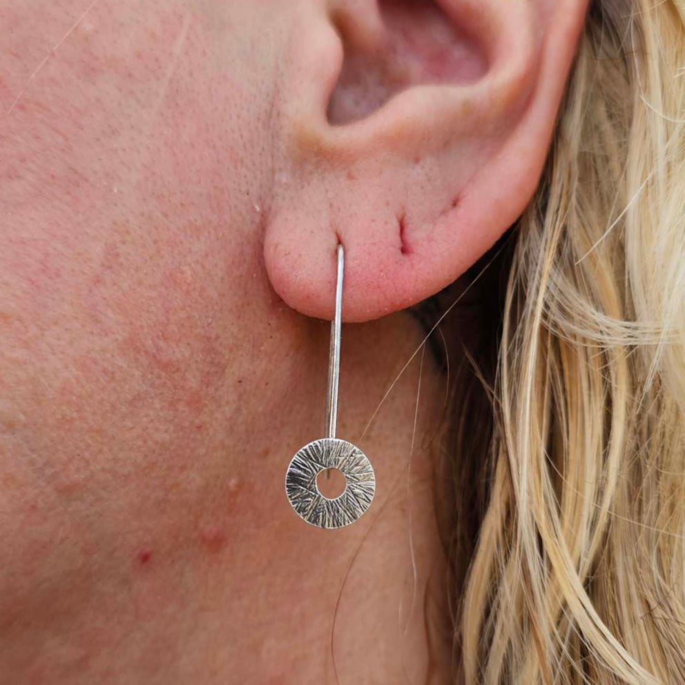 Woman with blond hair wearing silver Manifestation Earrings drops by Jaclyn Nicole