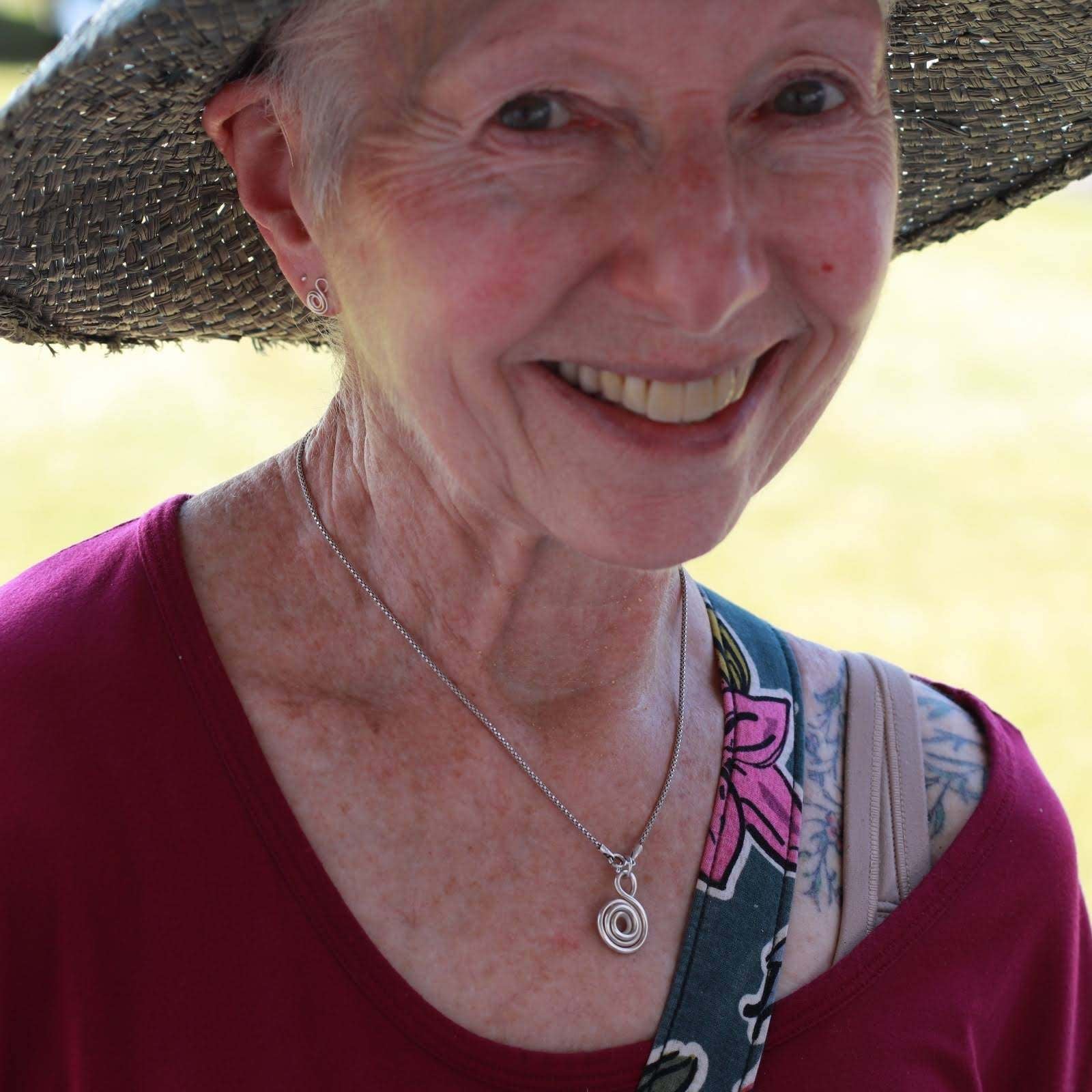 Smiling woman wearing a love and Gratitude necklace around her neck.