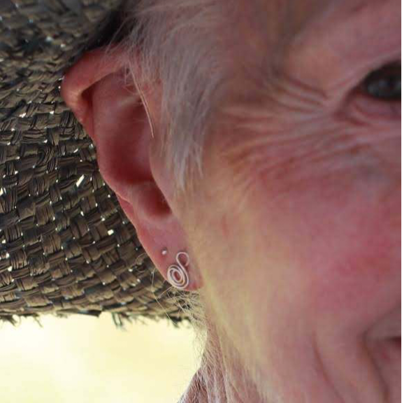 Woman with a hat wearing stud silver Gratitude earrings.