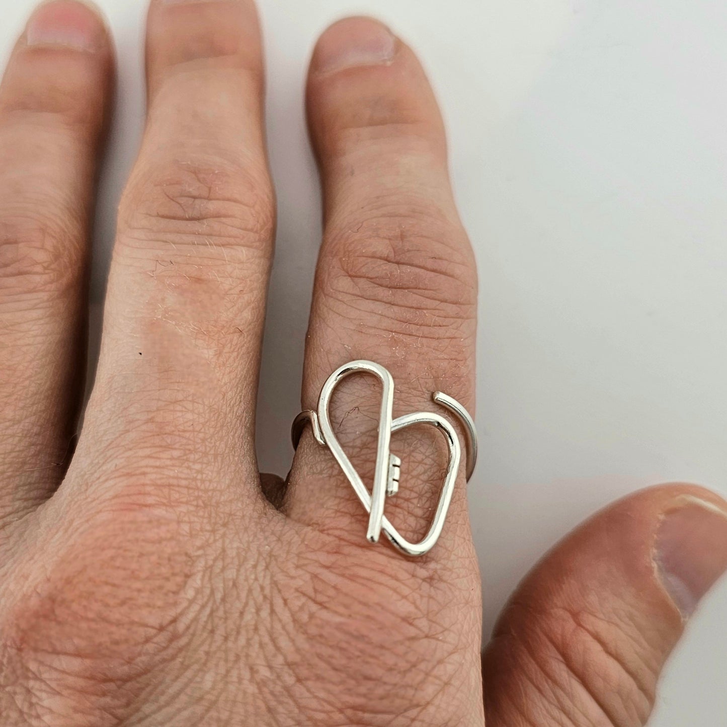 Woman's hand with a silver heart ring with a key in the middle.