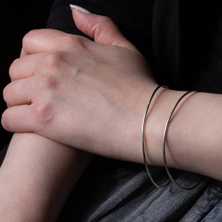 Woman crossing her hand to her other arm wearing a silver cuff bracelet on her wrist.