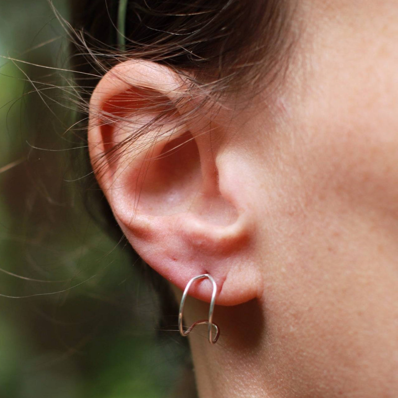 Silver lightweight earrings worn on a woman's earlobe