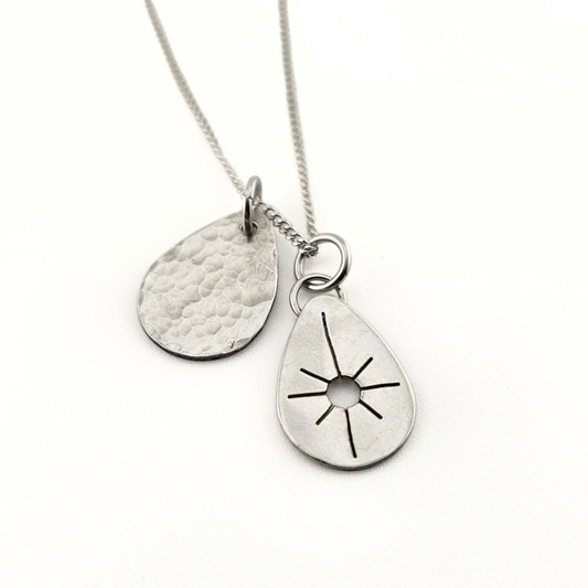 2 piece silver pendant on a white background