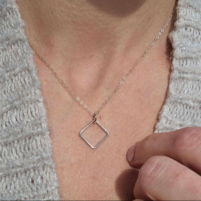 Woman with a grey sweater and a sterling silver square necklace symbolizing box breathing.