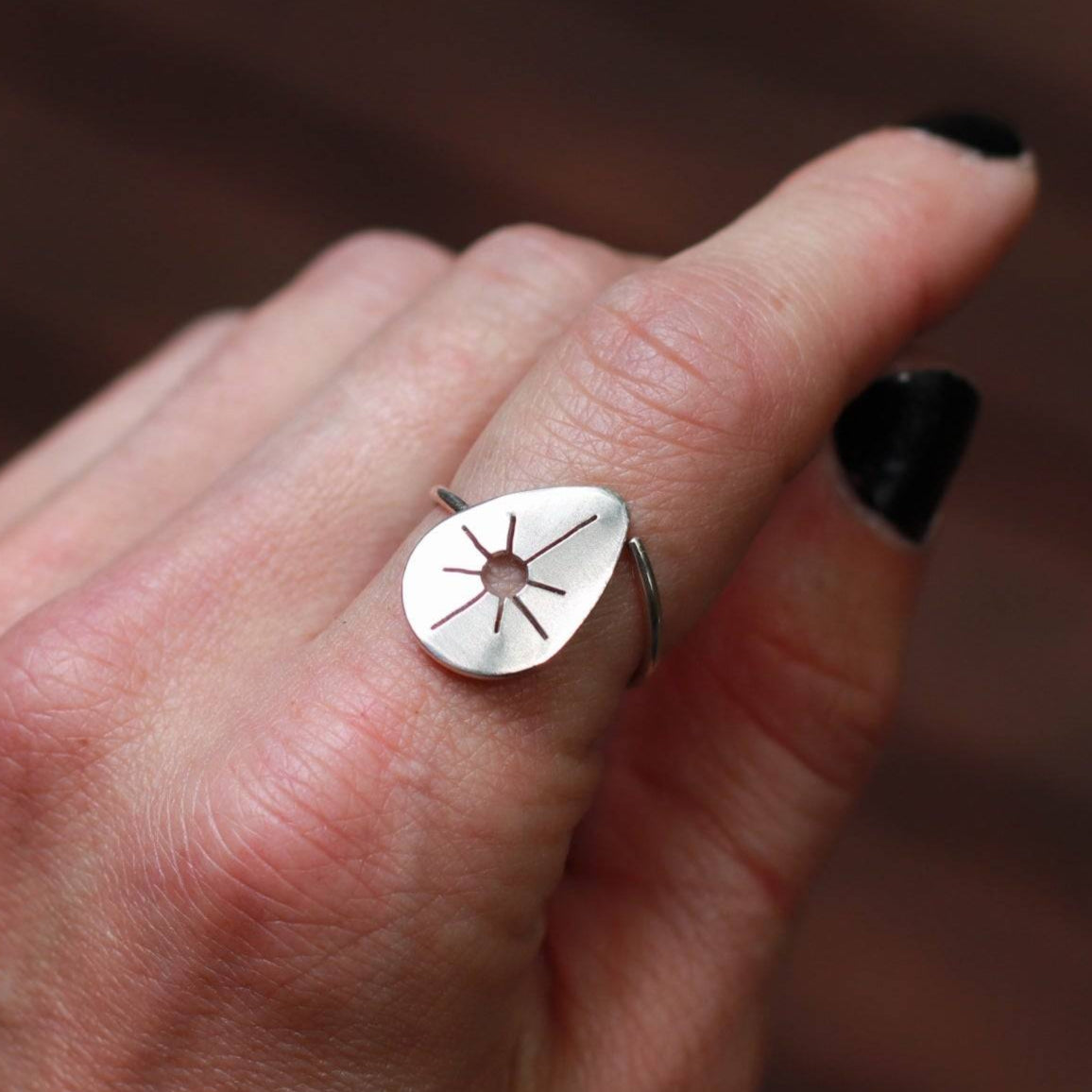 Sun drop ring worn on woman's pointer finger.