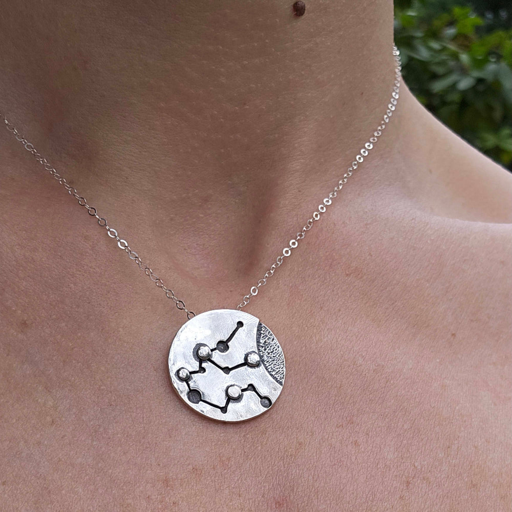 Silver Aquarius zodiac necklace on woman's neck