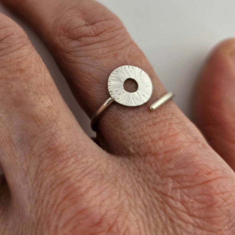 Silver manifestation ring on a woman's pointer finger.