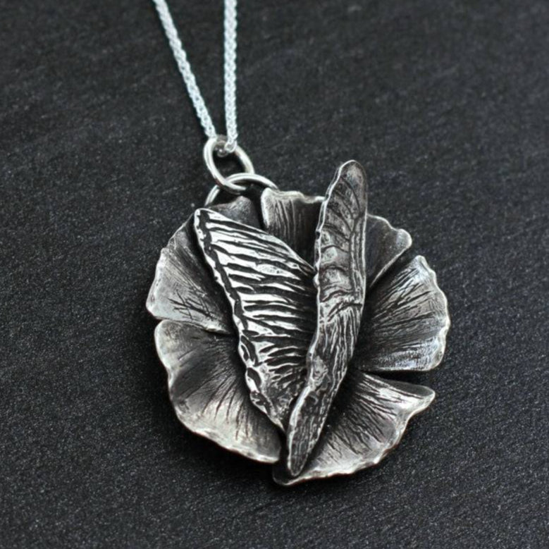 Handmade sterling silver pendant Butterfly Necklace landing on a flower with chain.