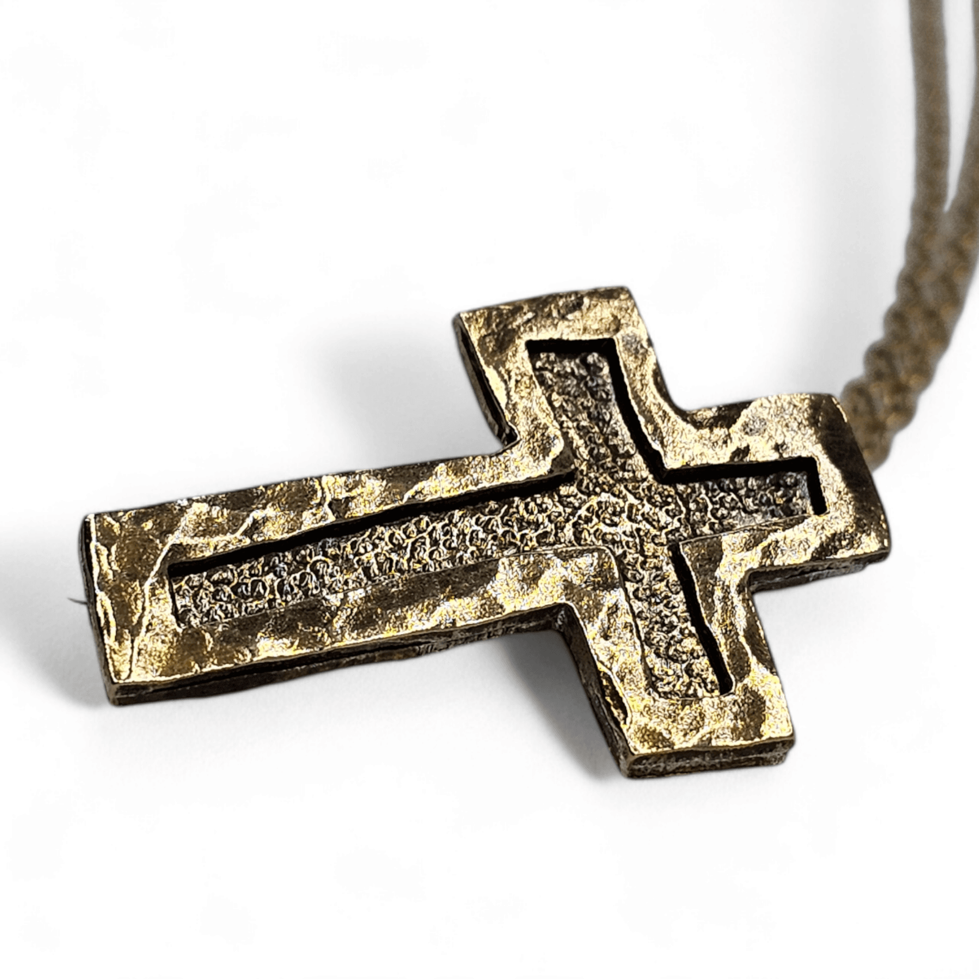 a gold Christian necklace cross laying sideways on a white background