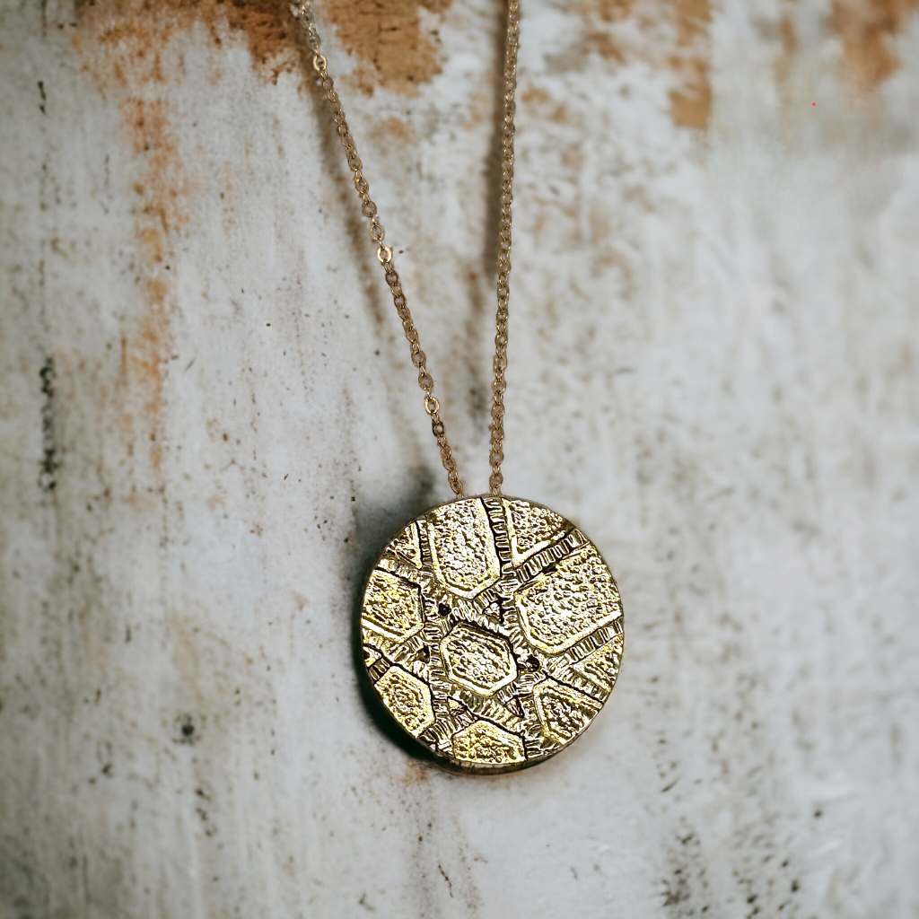 a gold pendant necklace on a worn background.