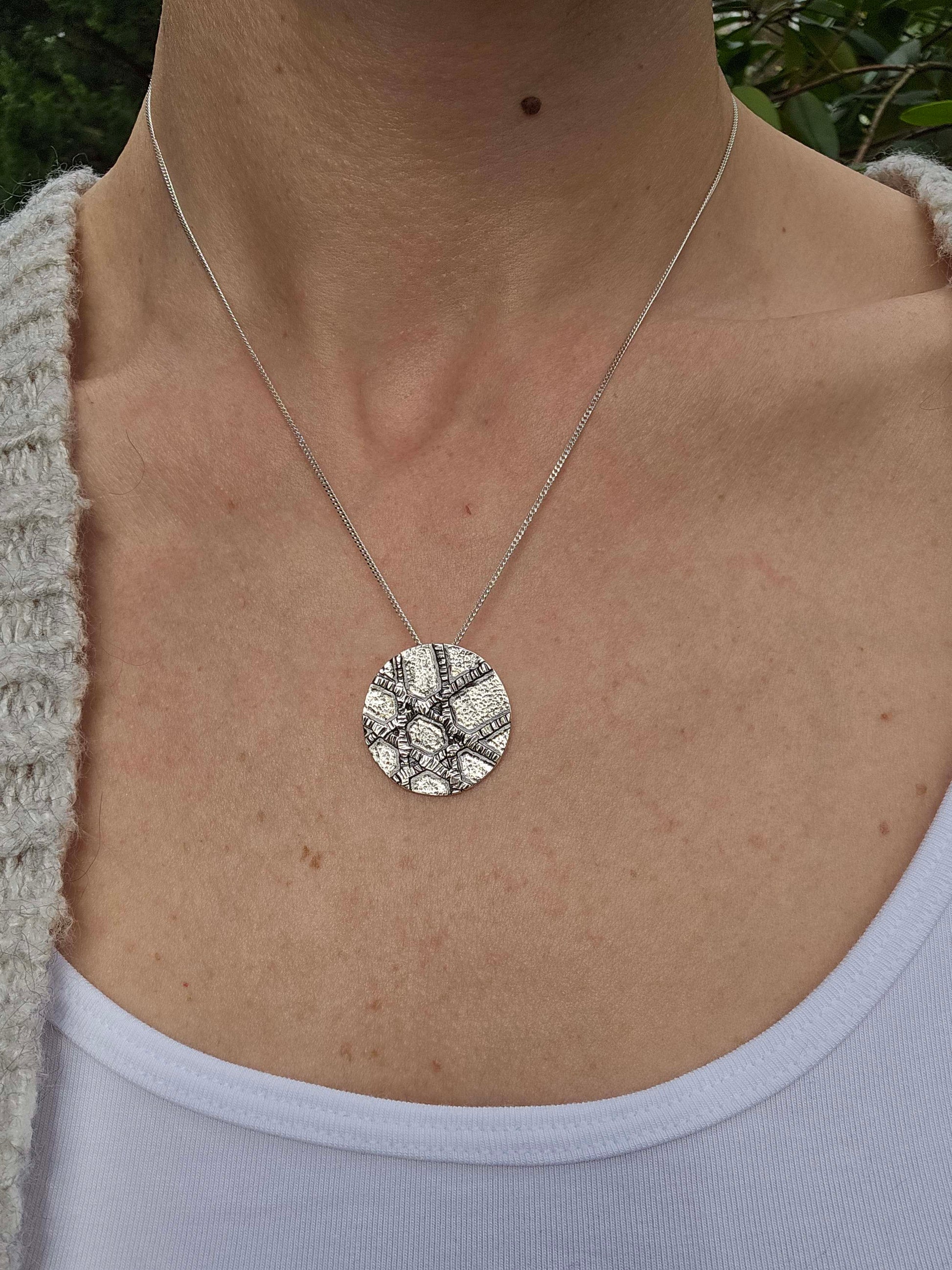 a woman wearing a white shirt and silver pendant necklace.