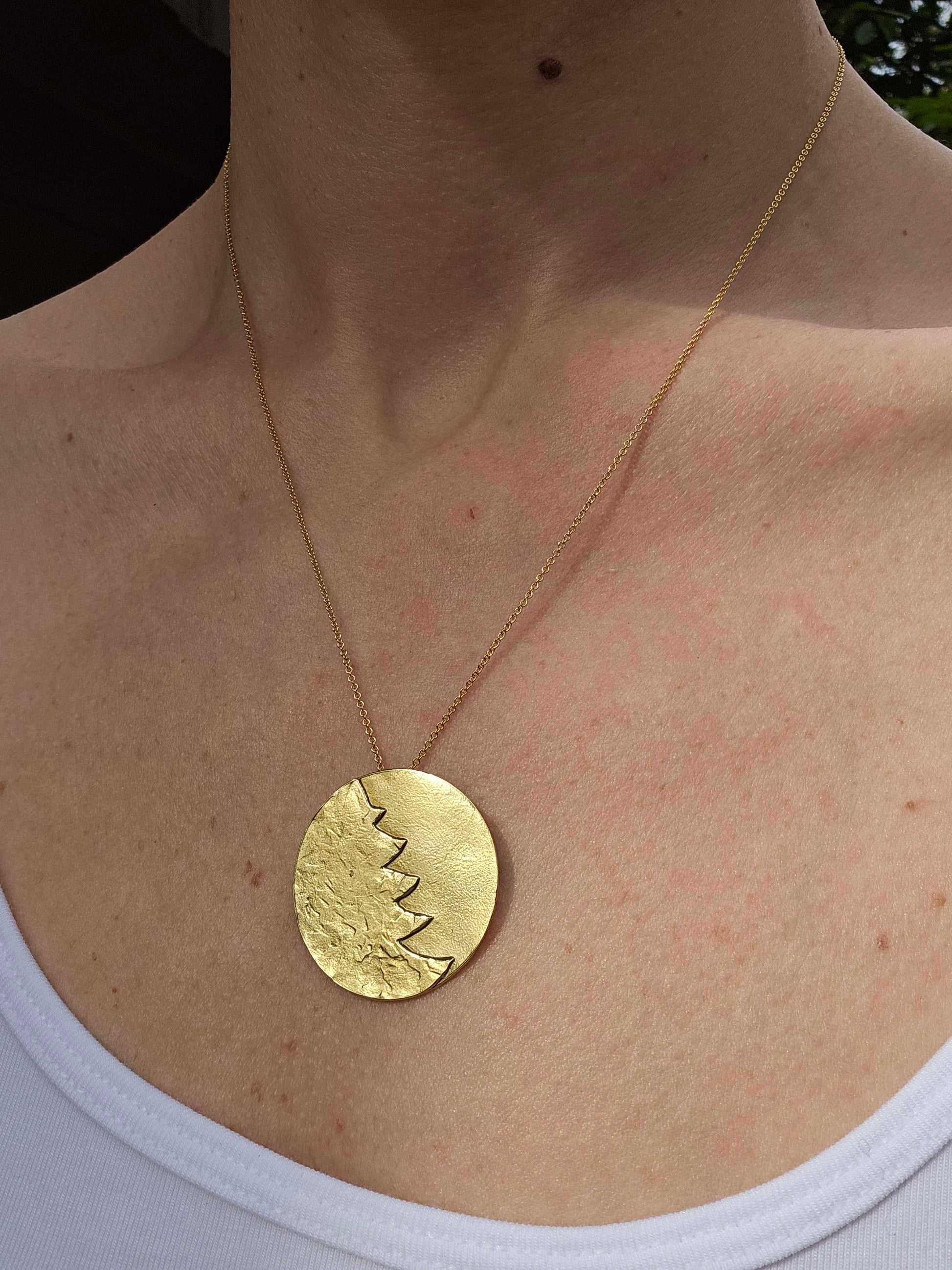 Woman wearing a gold pendant necklace.