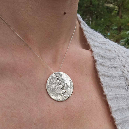 Woman wearing a silver pendant Christmas necklace.